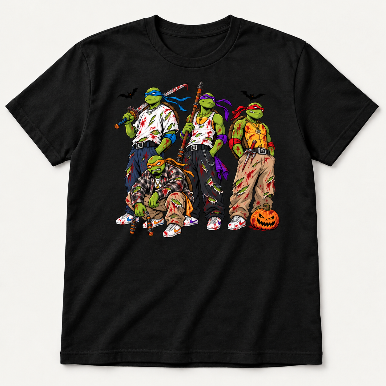 Black graphic T-shirt featuring four masked green turtles in torn streetwear, red splatter, bats and an orange pumpkin.