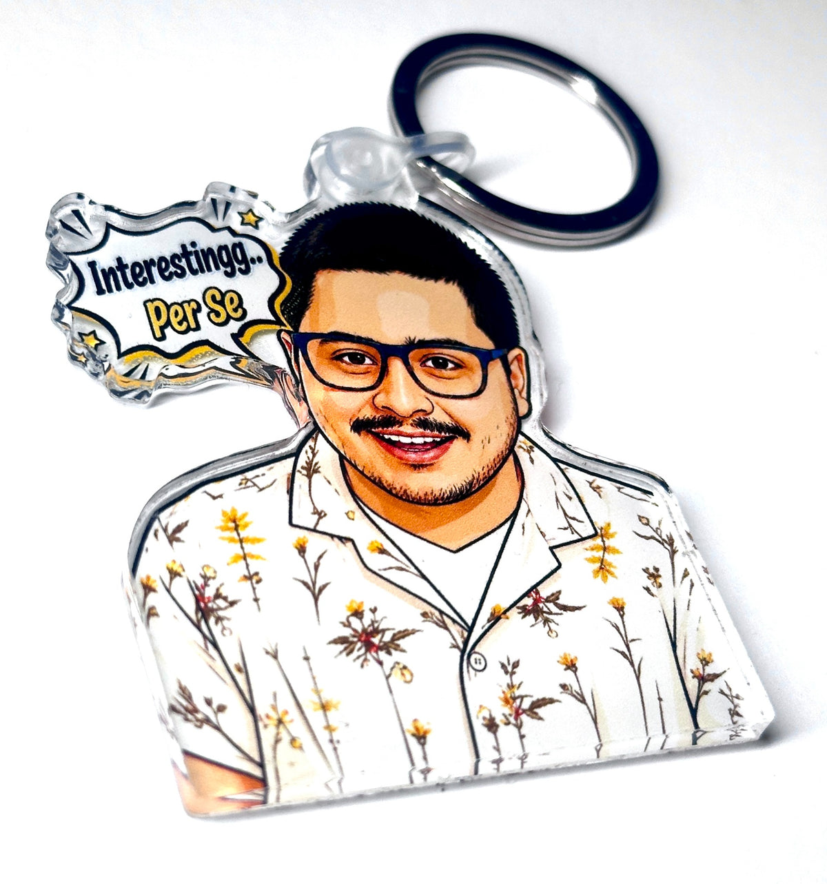 Funny reaction portrait acrylic keychain with glasses, floral shirt, and speech bubble reading Interestingg Per Se, angled product photo