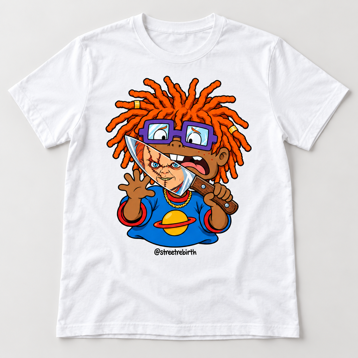 White graphic T-shirt with a caramel-skinned cartoon boy, orange locs, purple glasses and a spooky doll face reflected in a knife